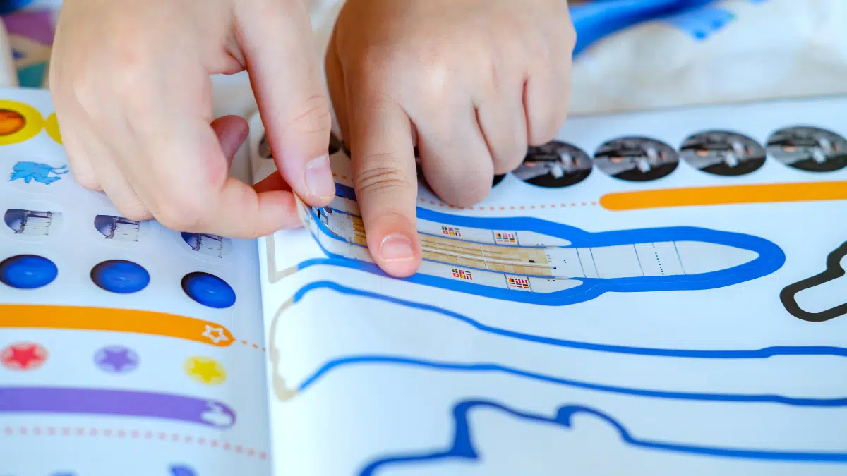 Atividades Educacionais Para Potencializar a Aprendizagem - iEducação Crianças colando adesivo.
Imagem: feitos por Ratchapoom Anupongpan de Getty Images