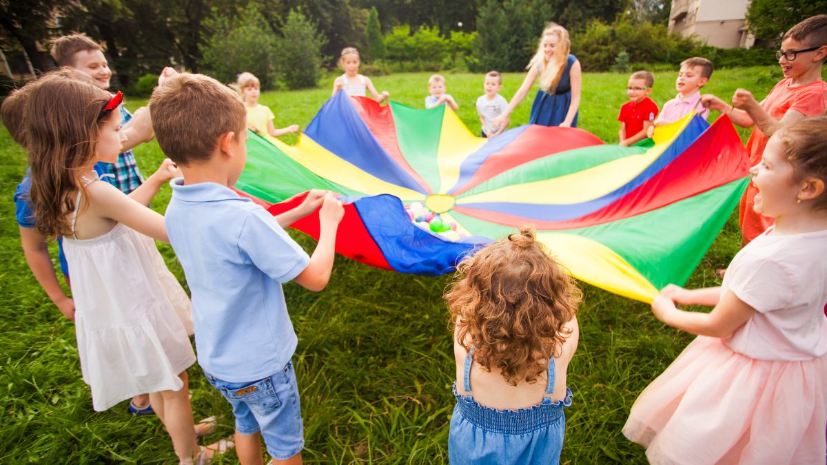 Crianças brincando com tecido colorido.
