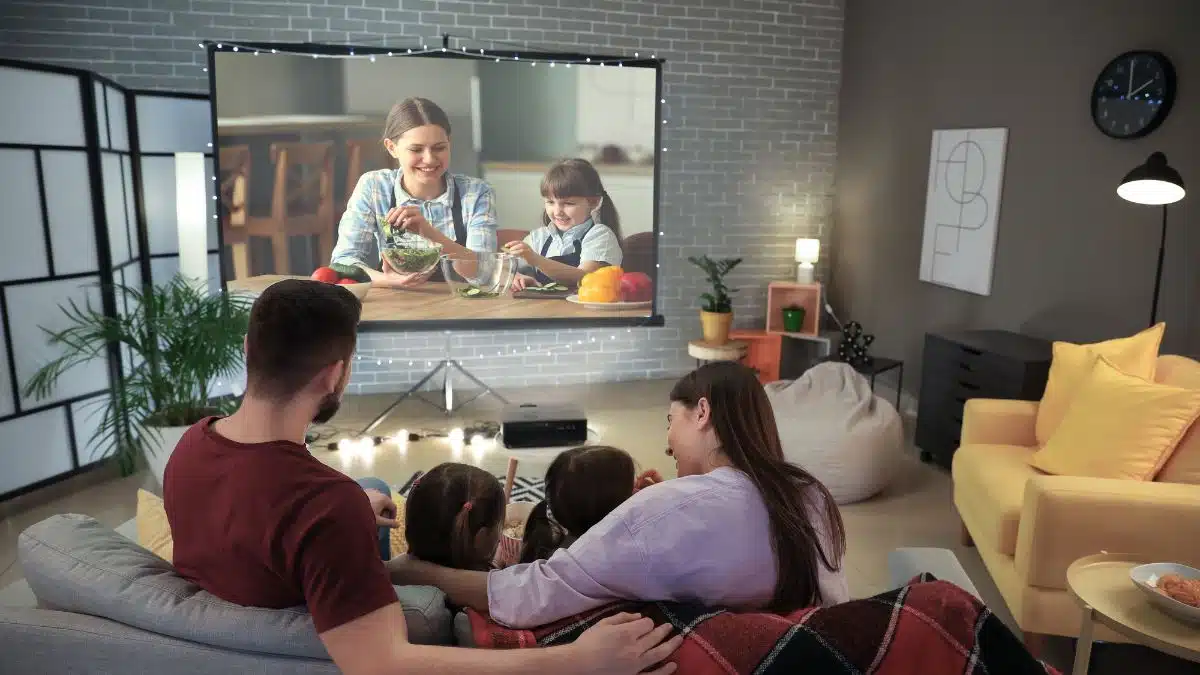 Atividades e Brincadeiras Educativas para Colônia de Férias - iEducação Família assistindo filme na sala.